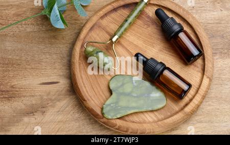 Bouteille en verre brun avec une pipette, masseur à main en pierre pour les procédures cosmétiques sur un fond en bois, vue de dessus Banque D'Images