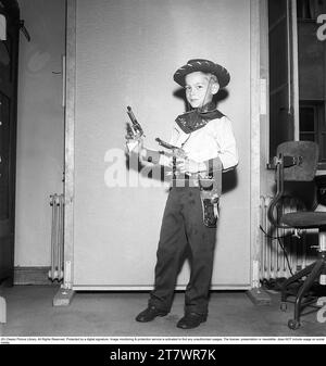 Garçon dans les années 1950 Un garçon est vêtu de vêtements de cow-boy, chemise, étui de pistolet et chapeau de cow-boy et tient deux revolvers jouets. 1950. Kristoffersson réf. AZ47-10 Banque D'Images