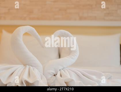 Serviettes en forme de cygne blanc sur le lit pour accueillir de nouveaux clients dans un hôtel de luxe dans une station balnéaire Banque D'Images