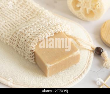 Barres de savon beige bio faites à la main dans un sac économiseur de savon près de l'éponge naturelle gros plan. Produits naturels à base de plantes Banque D'Images