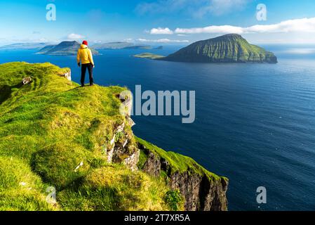 Randonneur debout au sommet d'une falaise admirant la vue sauvage, Nordradalur, l'île de Streymoy, les îles Féroé, le Danemark, Europe Banque D'Images