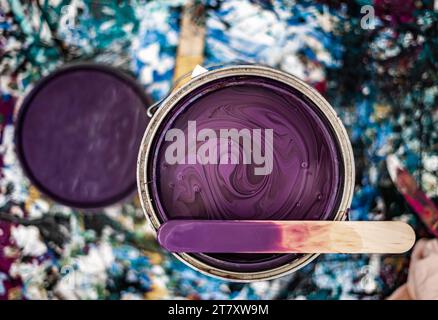 Boîte de peinture ouverte non mélangée Close Up Violet bâton de mélange Top Paint Mess fond Banque D'Images