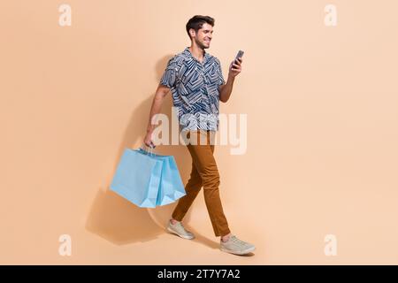 Photo de corps pleine grandeur de jeune shopaholic occupé ordre taxi pour rentrer à la maison avec d'énormes affaires de paquet de pile isolé sur fond de couleur beige Banque D'Images