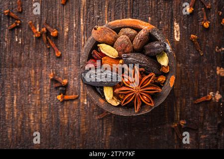 Épices de Noël pour la cuisson des biscuits, Stollen ou vin chaud dans un petit bol sur fond en bois. Banque D'Images