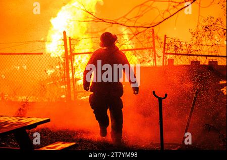 Un pompier incline la tête pour permettre à l'eau du tuyau de couler dans un incendie à la cour forestière RK Miles à Montpelier, VT, Nouvelle-Angleterre, USA. Banque D'Images