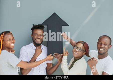 Équipe d'entreprise positive tenant une flèche noire pointant vers le haut. Banque D'Images