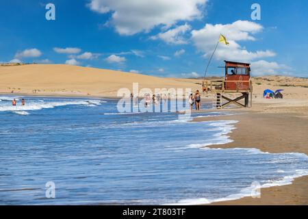 Tour de sauveteur et touristes marchant sur la plage à Barra de Valizas, station balnéaire / balneario le long de l'océan Atlantique, Rocha, Uruguay, Amérique du Sud Banque D'Images