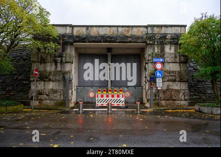 Une lourde porte en acier repose dans un cadre en pierre d'un barrage protégeant contre les inondations. La porte est fermée avec des lumières rouges et des barrières dépassant du gro Banque D'Images