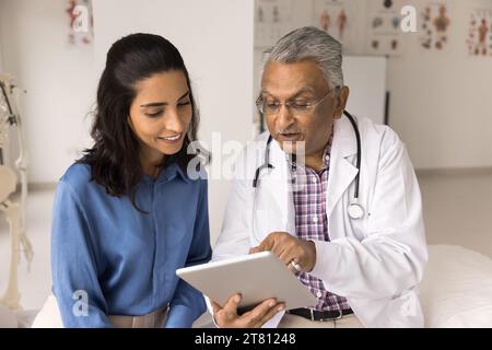 Médecin praticien indien positif montrant les résultats des tests médicaux au patient Banque D'Images