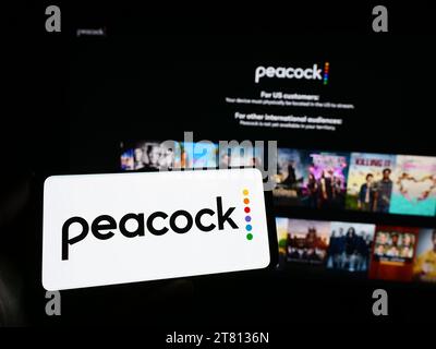 Personne détenant un smartphone avec le logo de la société américaine de services de streaming vidéo Peacock TV LLC devant le site Web. Concentrez-vous sur l'affichage du téléphone. Banque D'Images