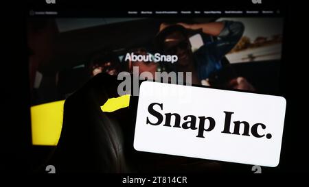 Personne détenant un smartphone avec le logo de la société américaine de médias sociaux Snap Inc. Devant le site Web. Concentrez-vous sur l'affichage du téléphone. Banque D'Images