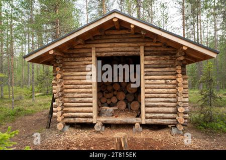 Une petite cabane en bois en bois garde les bûches sèches prêtes à être utilisées par les randonneurs pour faire un feu sur un sentier de randonnée dans le nord de la Finlande Banque D'Images