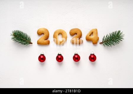 Biscuits sous la forme de numéros 2023 au centre sur le fond blanc décoré avec des brindilles de pin et des jouets de noël. Concept nouvel an, vue de dessus Banque D'Images