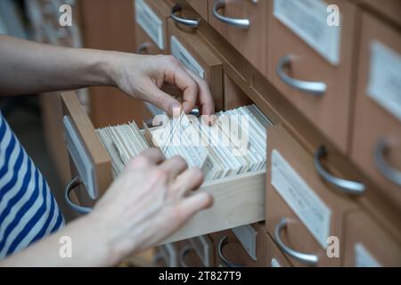 Femme étudiante trouvant des cartes de livre dans le catalogue d'index de carte d'université dans la bibliothèque. Banque D'Images