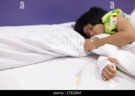 Les patients atteints de fièvre de la main de l'enfant ont un tube IV à l'hôpital. Petite fille portant le sommeil de tube IV dans la salle de lit d'urgence usi pour la leucémie coma du cancer, enfant Banque D'Images