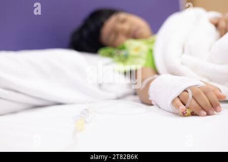 Les patients atteints de fièvre de la main de l'enfant ont un tube IV à l'hôpital. Petite fille portant le sommeil de tube IV dans la salle de lit d'urgence usi pour la leucémie coma du cancer, enfant Banque D'Images