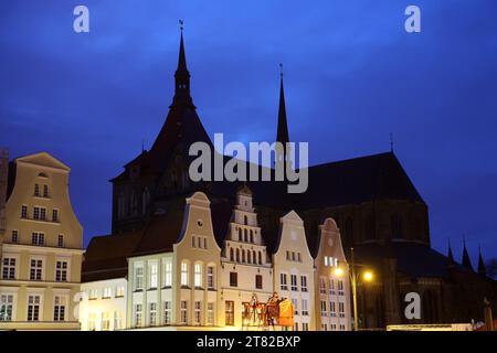 Rostock, Allemagne. 15 novembre 2023. La silhouette sombre de St. L'église de Marie dans le centre-ville domine les maisons illuminées le soir. Les églises de Mecklenburg-Vorpommern veulent économiser de l'énergie pendant la saison froide. Outre les aspects financiers, il s'agit également de la protection du climat. Cependant, il devrait être possible d'éclairer les bâtiments de l'extérieur à nouveau cet hiver. Crédit : Bernd Wüstneck/dpa/Alamy Live News Banque D'Images