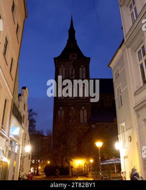 Rostock, Allemagne. 15 novembre 2023. Dans la soirée, la silhouette sombre de St. L'église de Marie dans le centre-ville domine entre les maisons illuminées. Les églises de Mecklembourg-Poméranie occidentale cherchent à nouveau à économiser de l'énergie pendant la saison froide. Outre les aspects financiers, il s'agit également de la protection du climat. Cependant, il devrait être possible d'éclairer les bâtiments de l'extérieur à nouveau cet hiver. Crédit : Bernd Wüstneck/dpa/Alamy Live News Banque D'Images