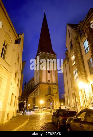 Rostock, Allemagne. 15 novembre 2023. L'église Petrikirche dans le centre-ville est illuminée par les maisons environnantes. Les églises de Mecklenburg-Vorpommern veulent économiser de l'énergie pendant la saison froide. Outre les aspects financiers, il s'agit également de la protection du climat. Cependant, il devrait être possible d'éclairer les bâtiments de l'extérieur à nouveau cet hiver. Crédit : Bernd Wüstneck/dpa/Alamy Live News Banque D'Images