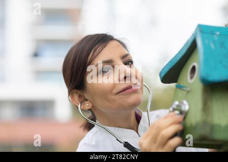 Médecin examine l'état de la boîte de nidification avec un stéthoscope protection de l'environnement Banque D'Images