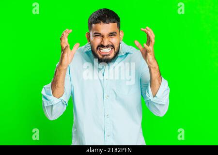 Irritée colère homme indien cris de stress tension problèmes se sent horreur désespoir peur choc surprise exprime rage nerveux, querelle. Jeune gars arabe isolé sur fond vert chroma clé Banque D'Images