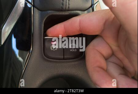 Conducteur activant le frein de stationnement électrique de sa voiture. Bouton de mise au point sélective Banque D'Images