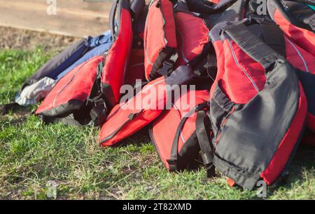 Gilets de sauvetage empilés sur l'herbe. Concept de tourisme actif sur les côtes en eaux douces Banque D'Images