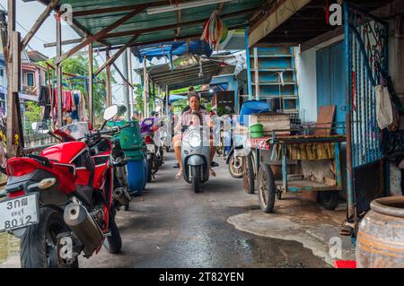 Les gens sur un scooter sur un sentier à côté d'un khlong ou canal avec des bâtiments résidentiels dans le district de Pattaya Chonburi Thaïlande Asie Banque D'Images