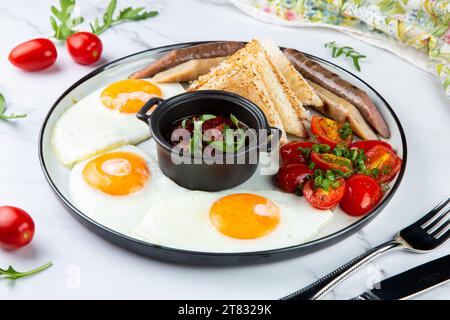 œufs brouillés avec tomates cerises, saucisses, sauce et pain vue latérale Banque D'Images