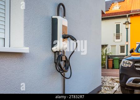 Wallbox sur un mur de maison familiale pour une recharge confortable de voiture électrique Banque D'Images