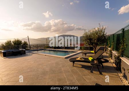 Deux chaises longues extérieures situées devant une piscine accueillante au coucher du soleil Banque D'Images