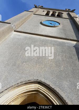 Gros plan d'une tour d'église historique en pierre contre un ciel bleu vif. Banque D'Images