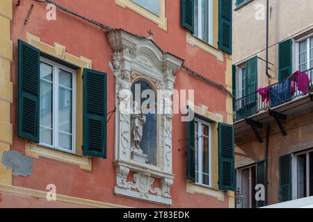 Sanctuaire votif dédié à la Vierge Marie entre une paire de fenêtres sur la façade d'un palais dans la vieille ville, finale Ligure, Savone, Ligurie, Italie Banque D'Images