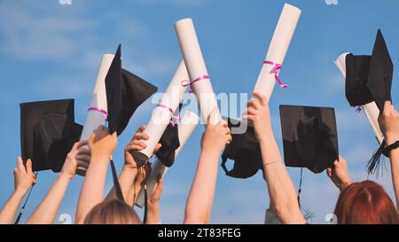 Les diplômés collégiaux élèvent leurs casquettes et leurs diplômes à la hausse. Banque D'Images