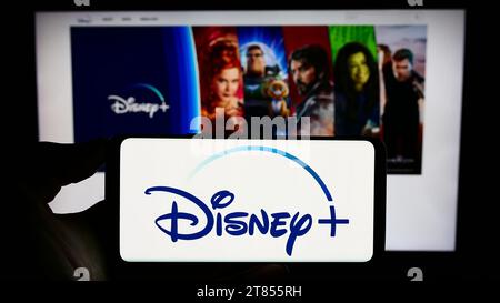 Personne détenant un téléphone cellulaire avec le logo du service américain de vidéo à la demande en streaming Disney plus devant la page Web de l'entreprise. Concentrez-vous sur l'affichage du téléphone. Banque D'Images