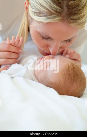 Gros plan, maman et bébé avec baiser sur le lit pour l'amour, les soins et le lien dans la relation. Bébé, sommeil ou rêve d'espoir, de vie future ou nouvelle avec croissance Banque D'Images