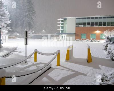 Immeuble de bureaux avec parking couvert de neige sous les lumières nocturnes Banque D'Images