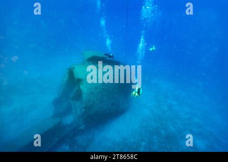 Les plongeurs passent au-dessus de l'épave d'un vieux cargo coulé dans des eaux bleues claires Banque D'Images