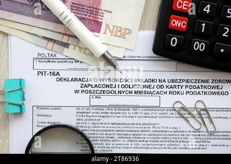 Déclaration du montant des cotisations d'assurance maladie payées et déduites de la carte d'impôt dans les mois individuels de l'année d'imposition, formulaire PIT-16a sur la table comptable avec stylo et factures d'argent zloty poli Banque D'Images