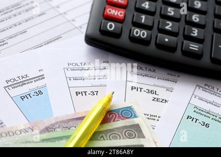 Déclaration du montant du revenu gagné ou de la perte subie, formulaires PIT-36, PIT-36L, PIT-37 et PIT-38 sur table comptable avec stylo et calculatrice Banque D'Images