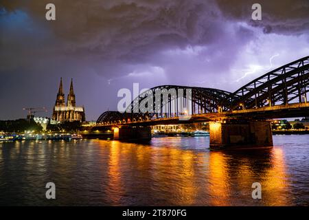 Nuages de foudre et de tempête au-dessus de la cathédrale de Cologne et du centre-ville. De forts éclairs éclairent la ville et se reflètent dans le Rhin Banque D'Images