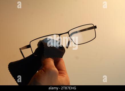 Une photo en gros plan de quelqu'un essuyant leurs lunettes avec un chiffon en microfibre noir. Banque D'Images