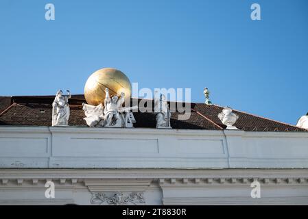 Vienne, Autriche 29 septembre 2023. Atlas portant globe doré - statues sur le toit du palais impérial Hofburg Banque D'Images