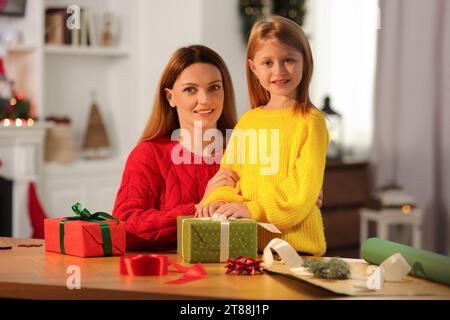 Emballage de cadeaux de Noël. Mère et sa petite fille avec des coffrets cadeaux à table dans la chambre Banque D'Images