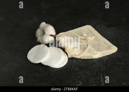 Tampons de coton, sac et fleur sur table noire Banque D'Images