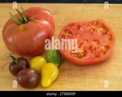 Fruits et légumes frais, tomates rouges, jaunes et vertes et juteuses colorées, dont une tranchée en deux montrant la chair et les graines, cultivées chez nous dans un potager australien Banque D'Images