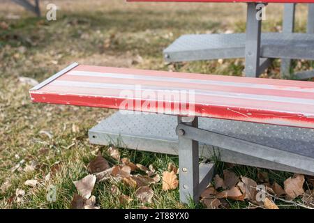 Un gros plan de gradins en métal rouge et blanc sur un terrain d'athlétisme. Banque D'Images