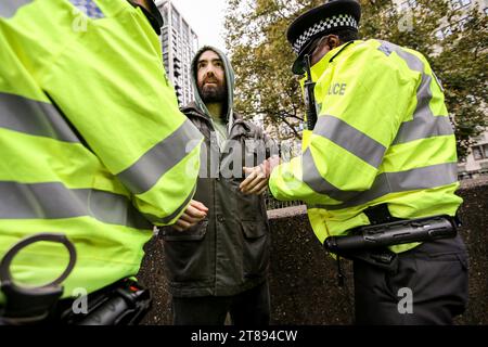 Londres, Royaume-Uni. 18 novembre 2023. Un manifestant est arrêté et menotté après avoir bloqué les routes avec sa bannière. Il suffit d'arrêter la marche du pétrole à travers Londres pour souligner la nécessité de changer la façon dont nous dépendons du pétrole et du gaz pour l'énergie. Ils soutiennent que le temps presse pour la planète et que le changement immédiat des combustibles fossiles est nécessaire. Ils affirment que le gouvernement emprisonne les manifestants pacifiques et protège les vrais criminels, les récompensant en autorisant plus de 100 nouveaux projets pétroliers et gaziers. Crédit : SOPA Images Limited/Alamy Live News Banque D'Images