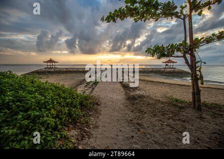 Lever de soleil magique avec des nuages dans le ciel. Ciel spectaculaire sur la plage de Sanur, Denpasar à Bali. Temple dans la mer calme le matin. Paysage tropical photographié Banque D'Images