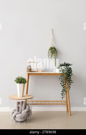 Table console avec différentes plantes d'intérieur, lanterne et cadre photo vide près du mur blanc Banque D'Images